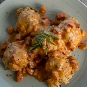 Top-down view of fluffy homemade savory biscuits drenched in Hawaiian-style ʻulu and Portuguese sausage gravy.