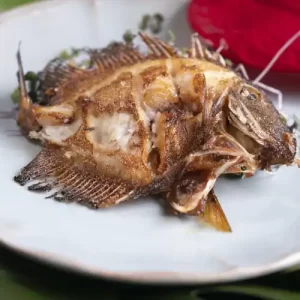 Golden brown crispy fried fish resting on a platter, showcasing Kalā DeSoto's simple local island-style recipe.